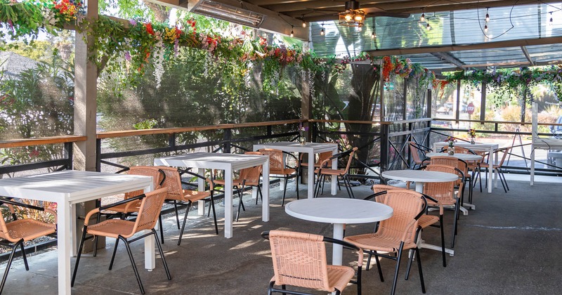 Covered patio with empty chairs and tables waiting for guests