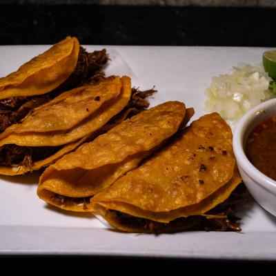 Birria tacos with broth.