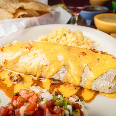 Burrito smothered in cheese sauce, with rice and salsa.