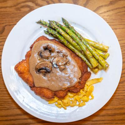 Pork Schnitzel served with asparagus, topped with mushroom gravy.
