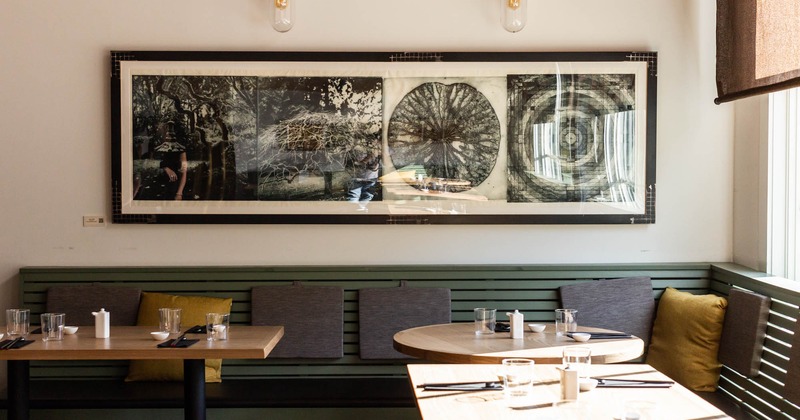 Interior, banquette seating by a wall decorated with pictures