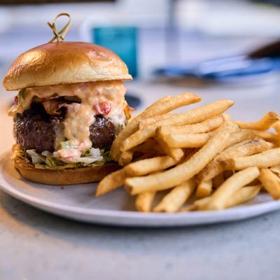 Burger with pimento cheese, bacon, lettuce, pickled green tomatoes, and a side of fries.