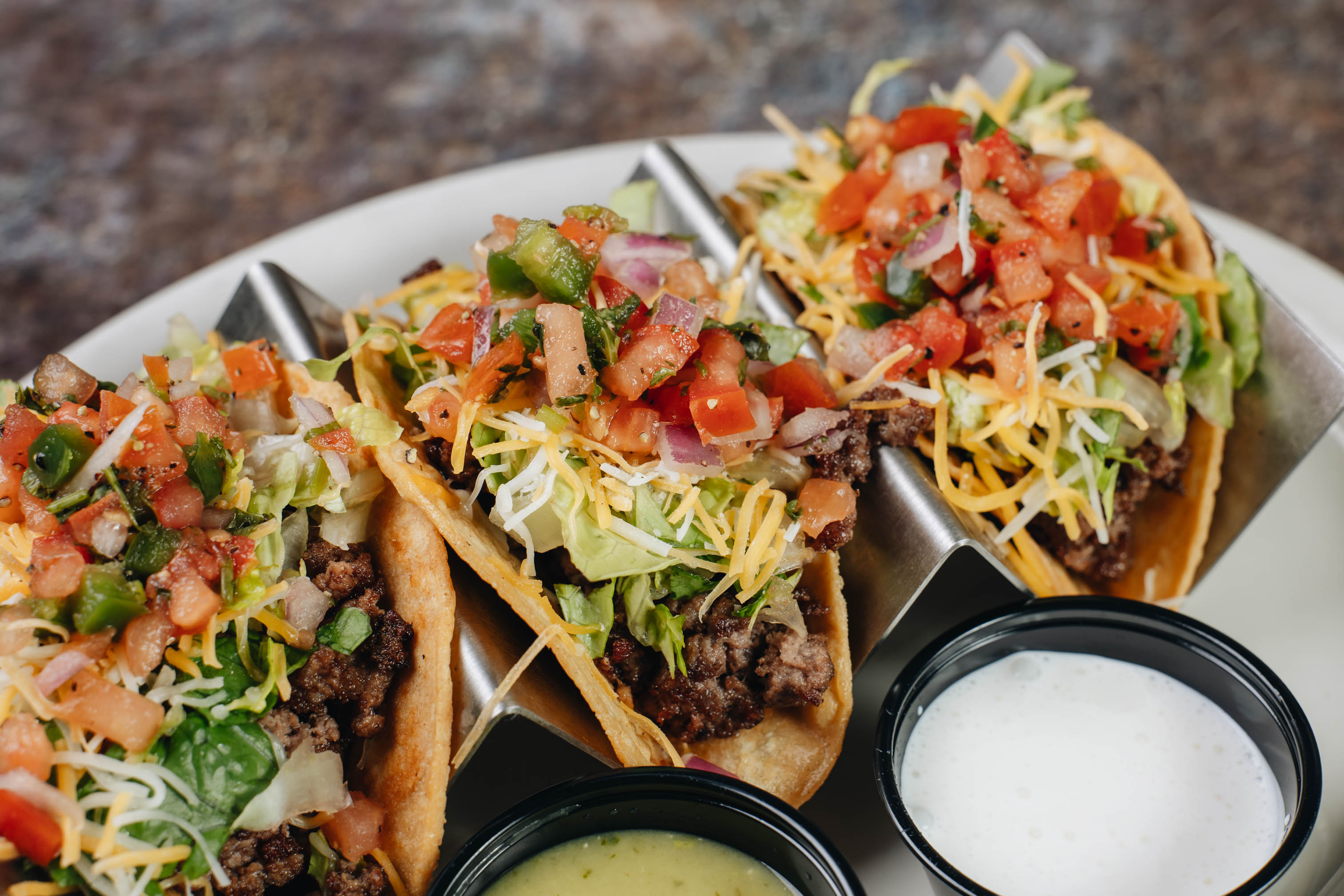 Three meat tacos served with salsa and sour cream