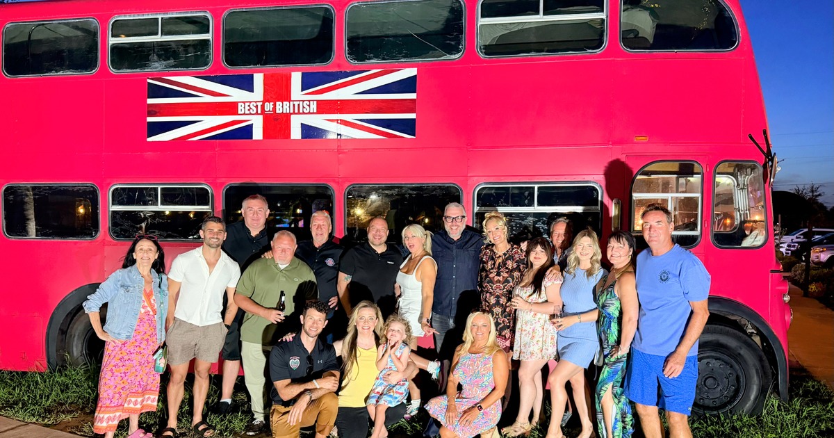 Group of people gathered in front of the iconic red double-decker bus