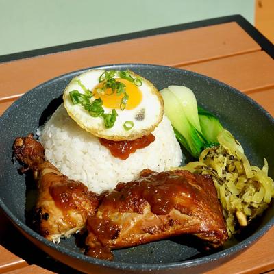 Spiced Braised Chicken Leg Quarter with white rice, pickles, fried egg, and vegetables.