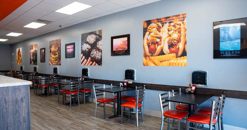 Interior, tables and chairs lined up next to the wall, framed pictures on the wall