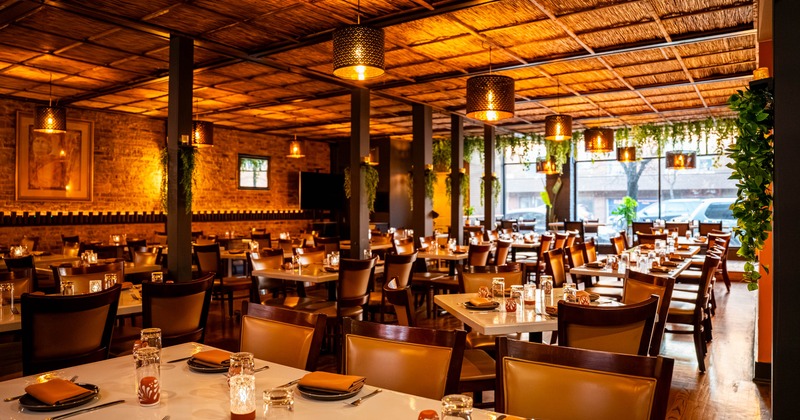 Interior dining area with wooden chairs and tables, and hanging lights