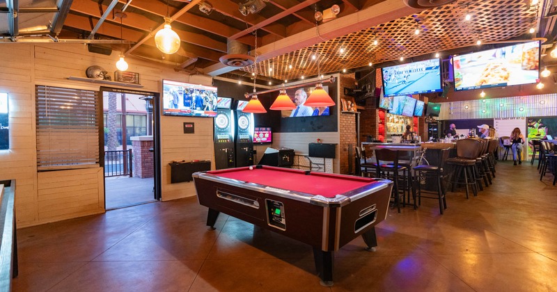 Room with pool table, bar behind