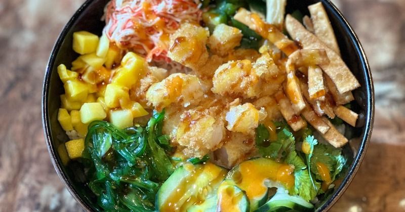 A colorful poke bowl on a wood-textured table