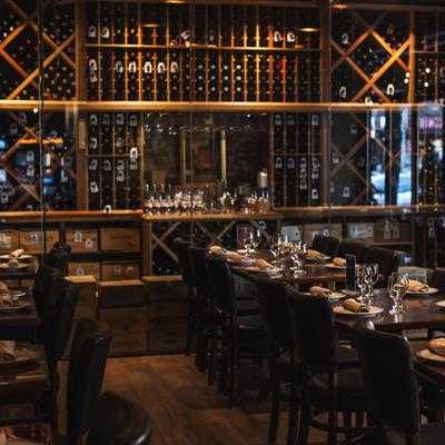 Restaurant dining area with wine wall and set tables.