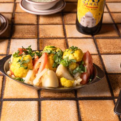 A plate with fresh cauliflower and potatoes cooked with herbs and spices.