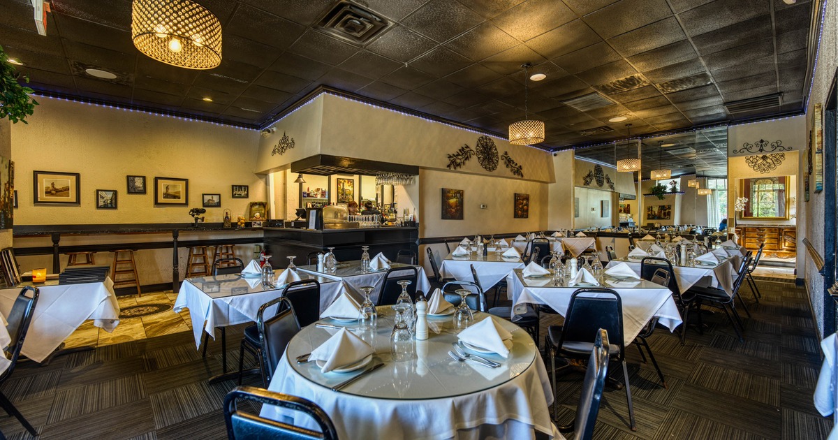 Elegant restaurant interior with round tables, white tablecloths, black chairs