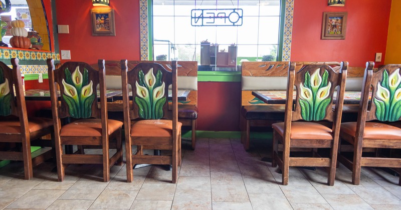 Interior, dining tables with wooden benches and massive wooden chairs, tile flooring