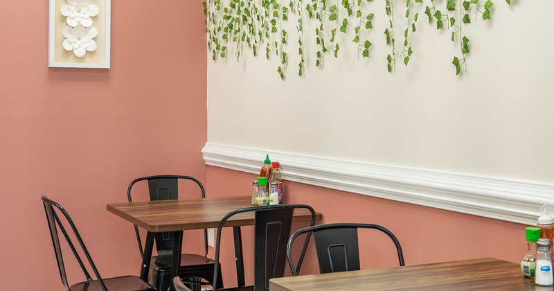 Interior - black metal chairs, wooden tables, decor: green ivy, wall lamp, a shelf with pink tulips