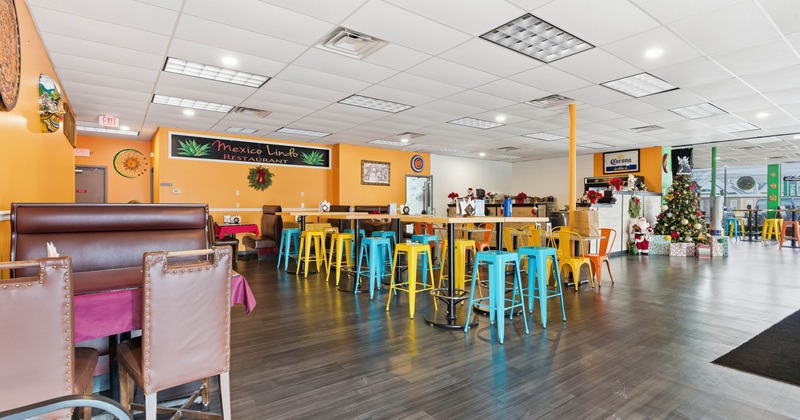 Interior with colorful decor -  high tables, yellow and blue stools, booths and a Christmas tree