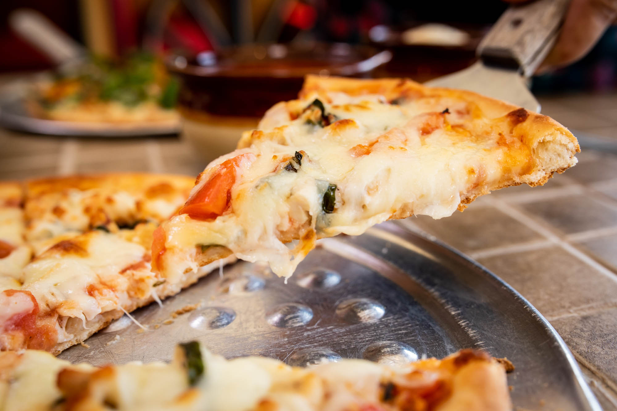 Taking a slice of pizza Napoli using pizza spatula, close-up