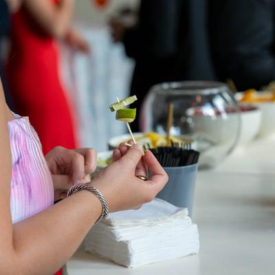 A guest holds a pick with lime slices on it while enjoying a lively event atmosphere.