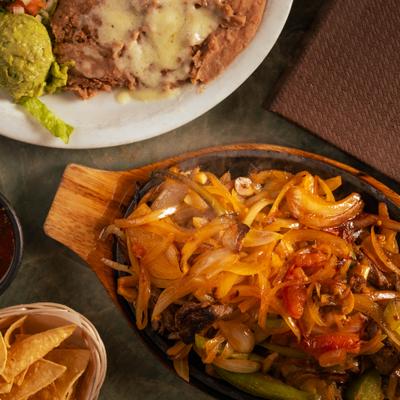 Steak Fajitas served with seperate plate of sides and nachos with a dip.