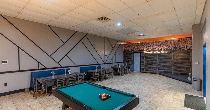 Modern lounge with a pool table in the foreground, tables along the side