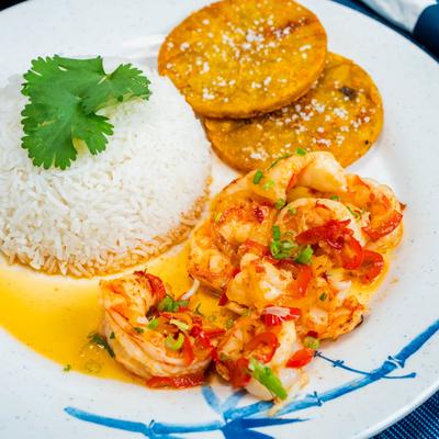 Grilled shrimp with peppers, rice, and fried green plantains.