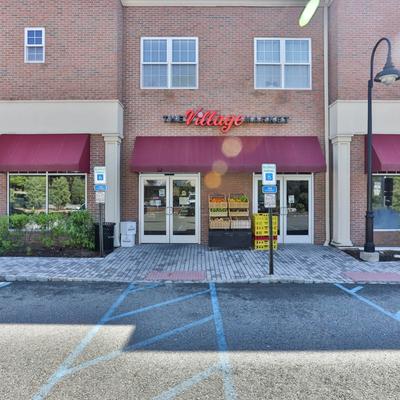 The Village Market storefront featuring a red awning and baskets of fresh produce.