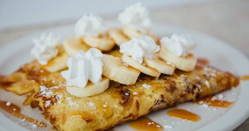 Crepes topped with banana slices and whipped cream