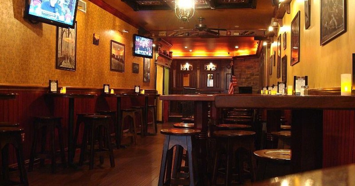 Interior with tables, chairs, TVs, and dim lighting