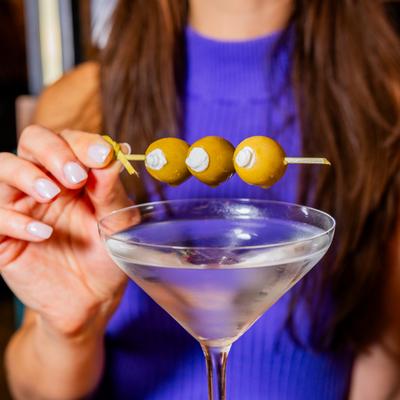 Hand holding up olives from a martini.
