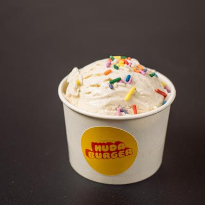 Vanilla Ice Cream served in a branded paper cup, topped with rainbow sprinkles.