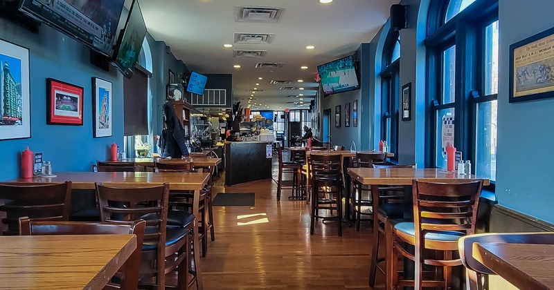 Interior, lined up tables and chairs, TV screens on the wall