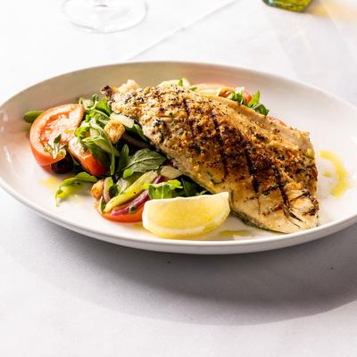 Grilled branzino fillet, with arugula, tomato, cucumber, onions, olives, capers, and croutons.