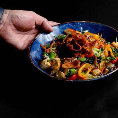 Chicken rice bowl, with peppers, onion, zucchini, mushrooms, carrots, broccoli, and sauce.