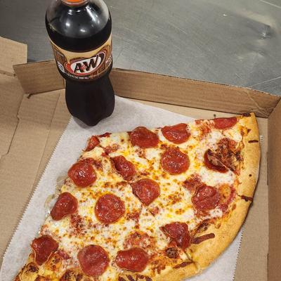 Two slices of pepperoni pizza in a box beside a bottle of soda.
