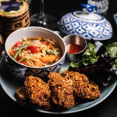 Crispy fried chicken and papaya salad, accompanied by greens and a dipping sauce.