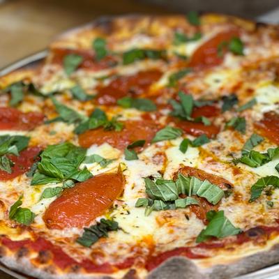 Margherita pizza, house-made red sauce, fresh tomato,  basil, fresh mozzarella.