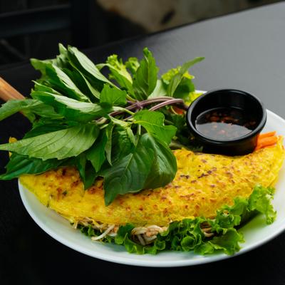 Vietnamese turmeric pancake served with fresh herbs and dipping sauce.