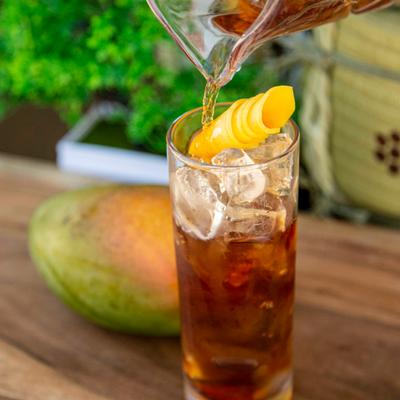 Close up of glass of iced mango tea getting poured on the table outside