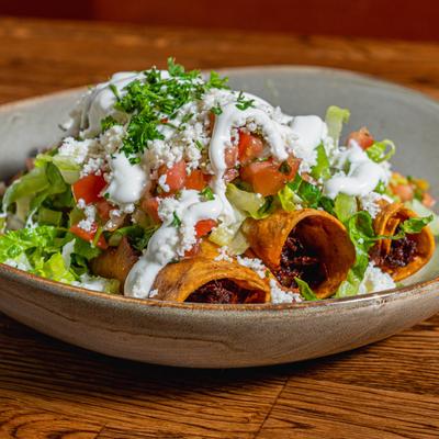 Crispy Chipotle Chicken flautas on a bed of shredded lettuce, guac, and pico de gallo.