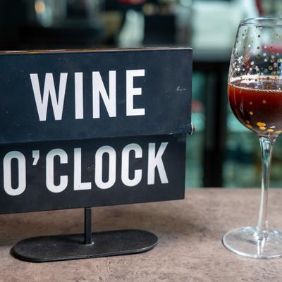 Wine O' Clock sign beside a wine glass on a counter.