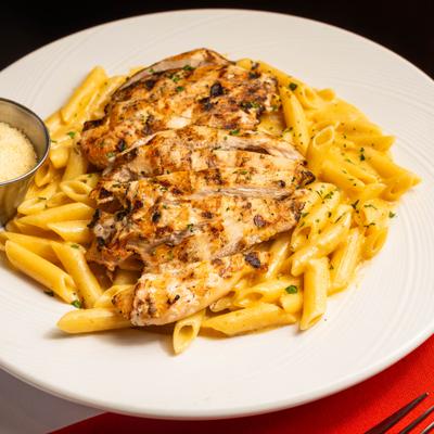 Chicken alfredo pasta with a cup of Parmesan