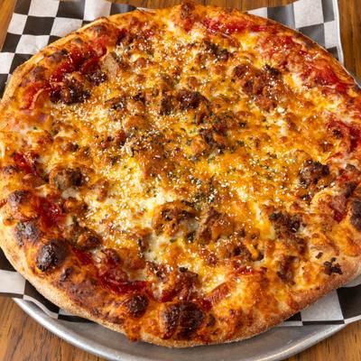 All meat pizza on a paper-lined tray.