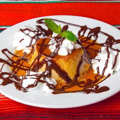 Mexican flan with whipped cream, caramel sauce, and chocolate drizzle.