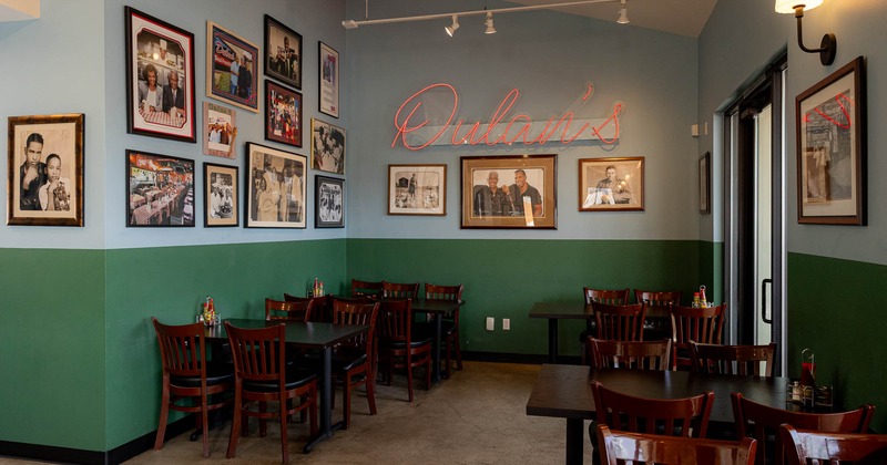 Interior seating area with framed photos,  dark wooden tables and chairs