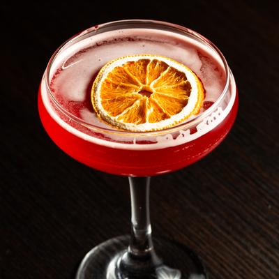 Cocktail in coupette glass garnished with dried orange wheel.