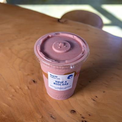 Peanut butter and berry smoothie in a clear plastic cup with a lid.