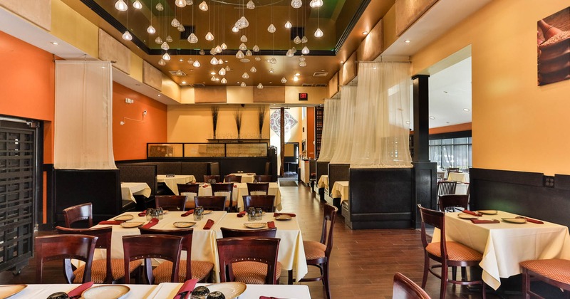 Upscale restaurant interior with pendant lights, white cloth tables, and warm-toned decor