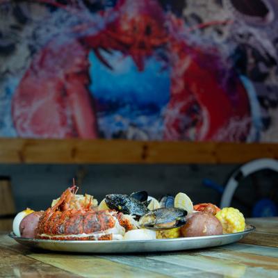 Seafood platter served on a wooden table with a lobster mural background.
