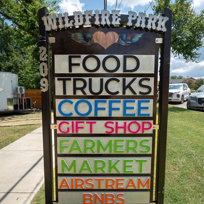 Wildfire Park sign listing food trucks, coffee, gift shop, farmers market, and lodging.