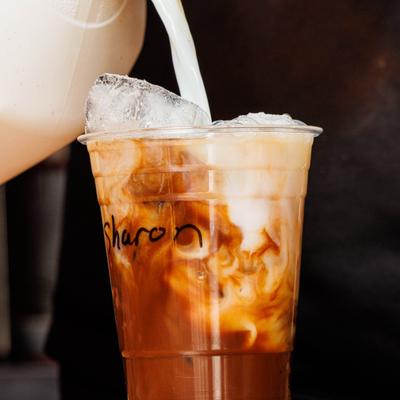 Iced coffee beverage with milk and ice cubes in a clear plastic cup.