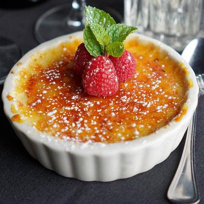Creme brulee topped with raspberries, mint, and powdered sugar.